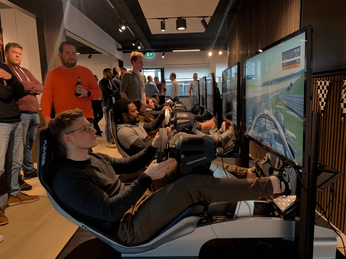 Collega's racen naast elkaar in F1-simulatoren tijdens een bedrijfsevent van WePlay United