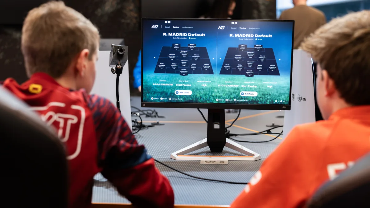Over de schouder van twee spelers die Real Madrid-tactieken bekijken op het PS5-scherm