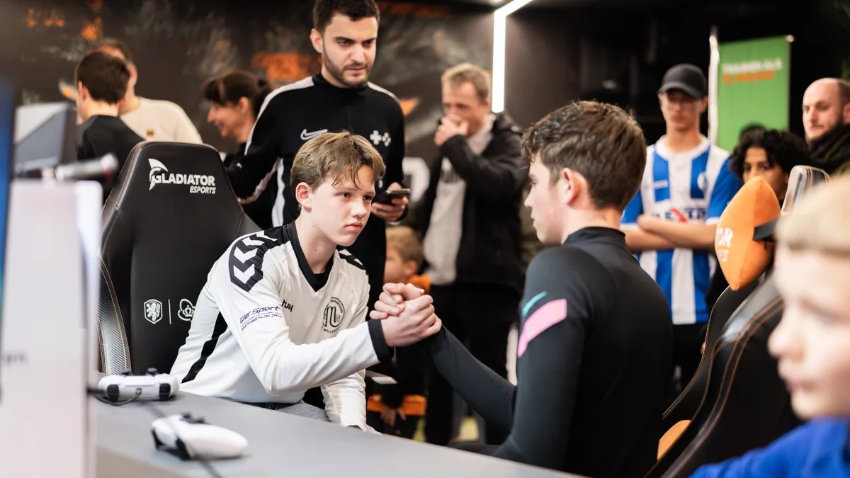 Twee spelers schudden handen na hun wedstrijd terwijl een WePlay-medewerker toekijkt
