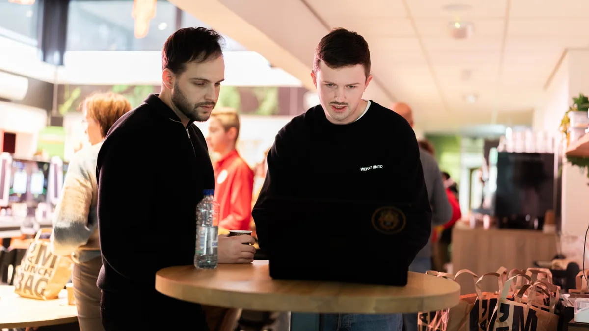 Twee WePlay United-medewerkers overleggen achter de laptop tijdens het toernooi
