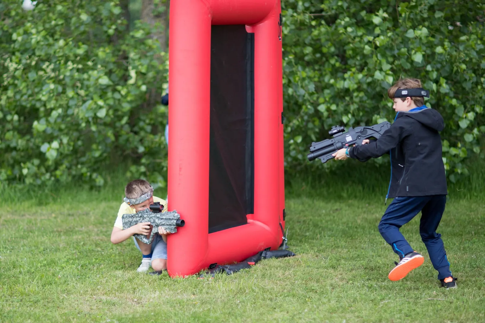 Twee kinderen in actie tijdens een lasergame bij opblaasbare hindernissen