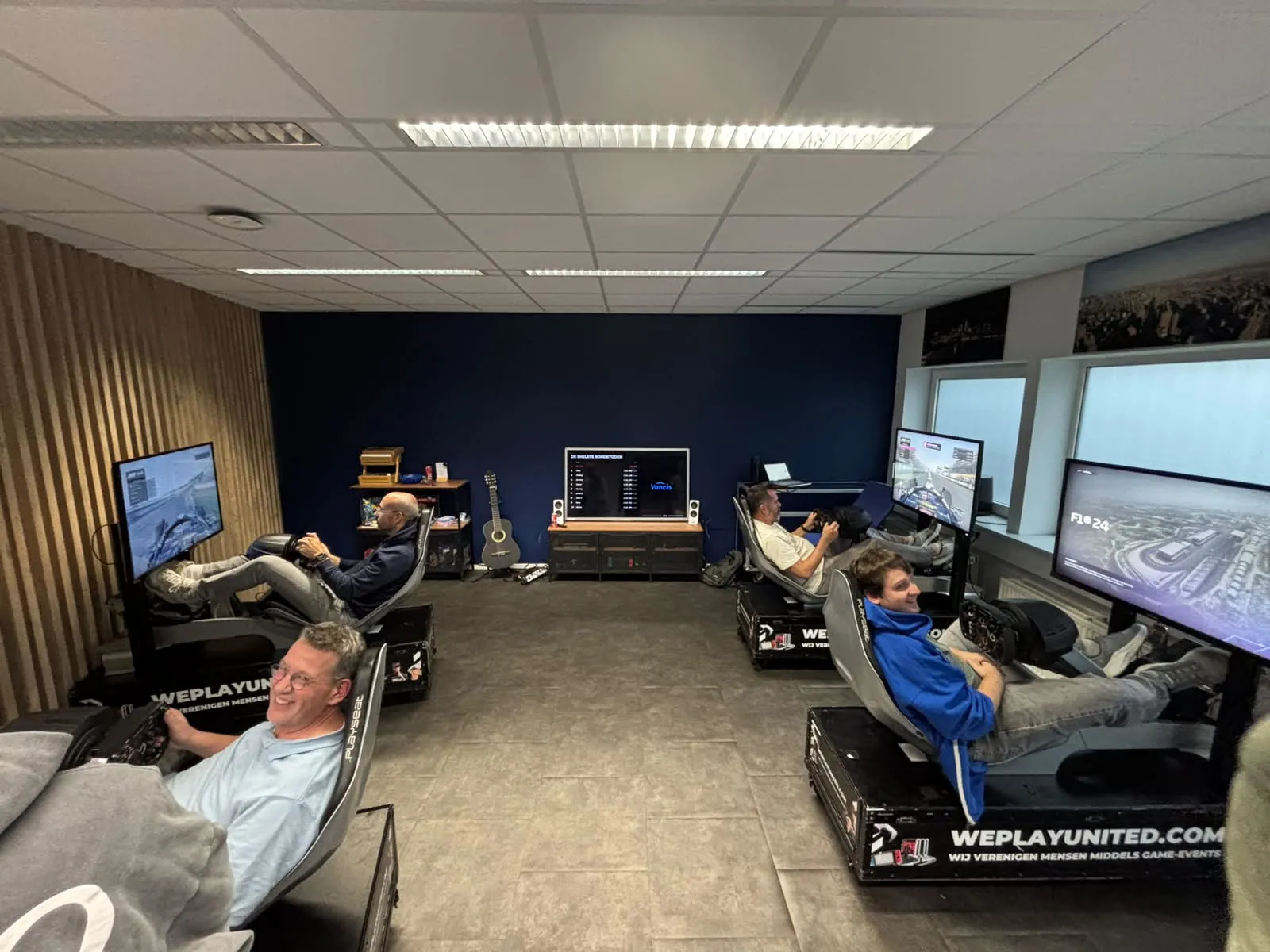 Vier F1-simulatoren van WePlay United bij Vancis in Almere, met een ranglijst van de snelste rondetijden op het middenscherm