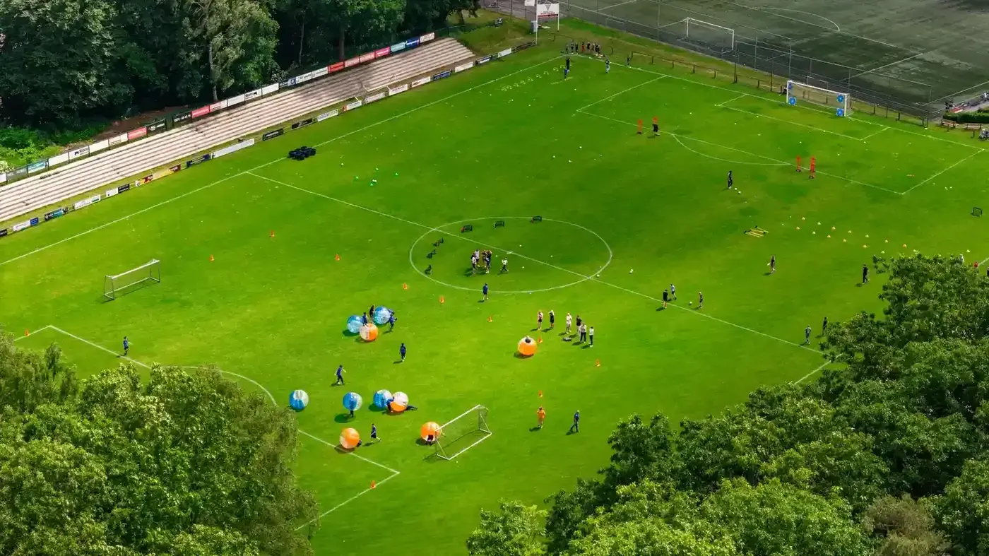 Luchtfoto van een groot bubbelvoetbal event op een voetbalveld met meerdere teams