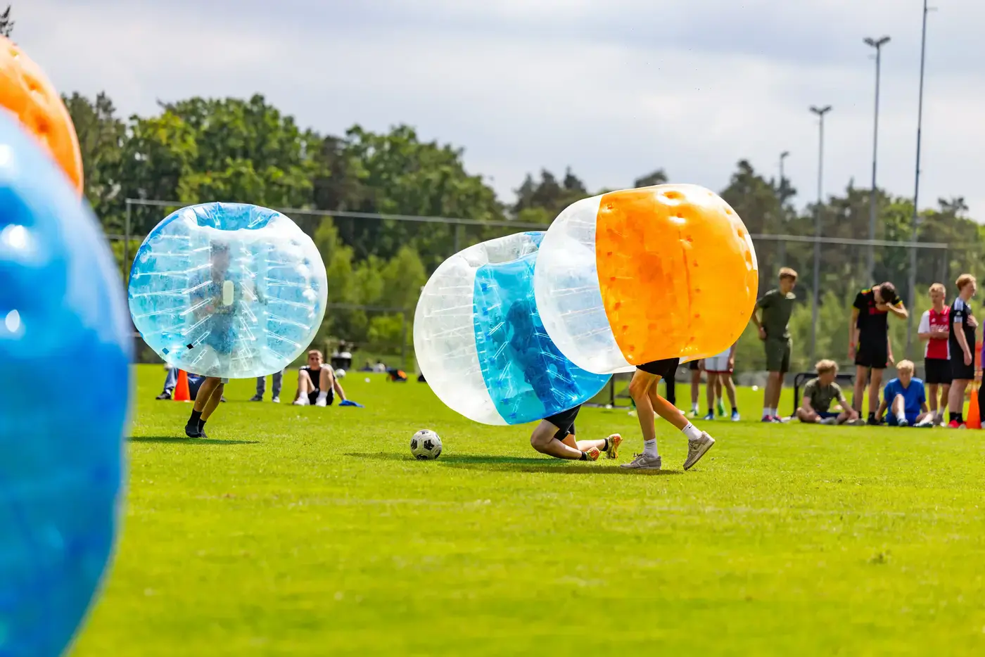 Groep collega's speelt bubbelvoetbal tijdens een bedrijfsuitje op een sportterrein