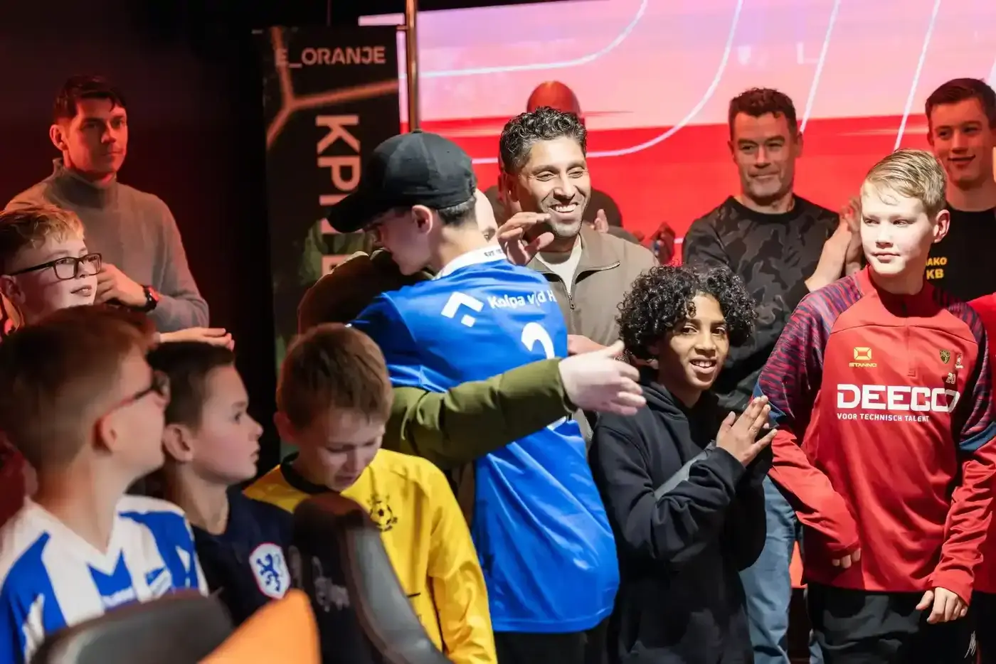 Jongeren in voetbalshirts spelen geconcentreerd FIFA op PlayStation 5 tijdens een toernooi