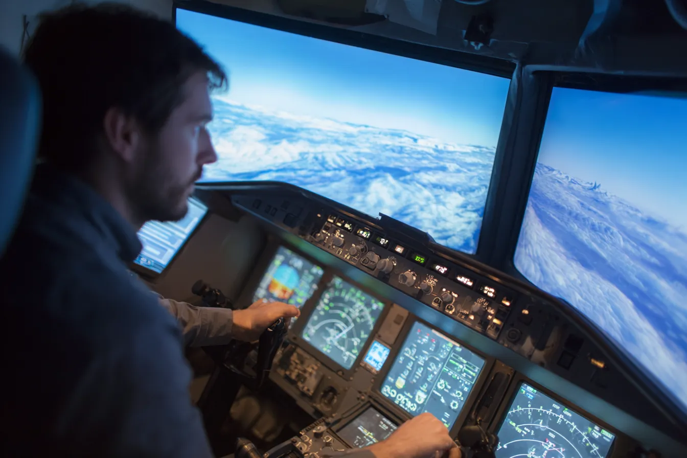 Persoon in vluchtsimulator met cockpit-controls en meeslepend scherm met uitzicht vanuit vliegtuig