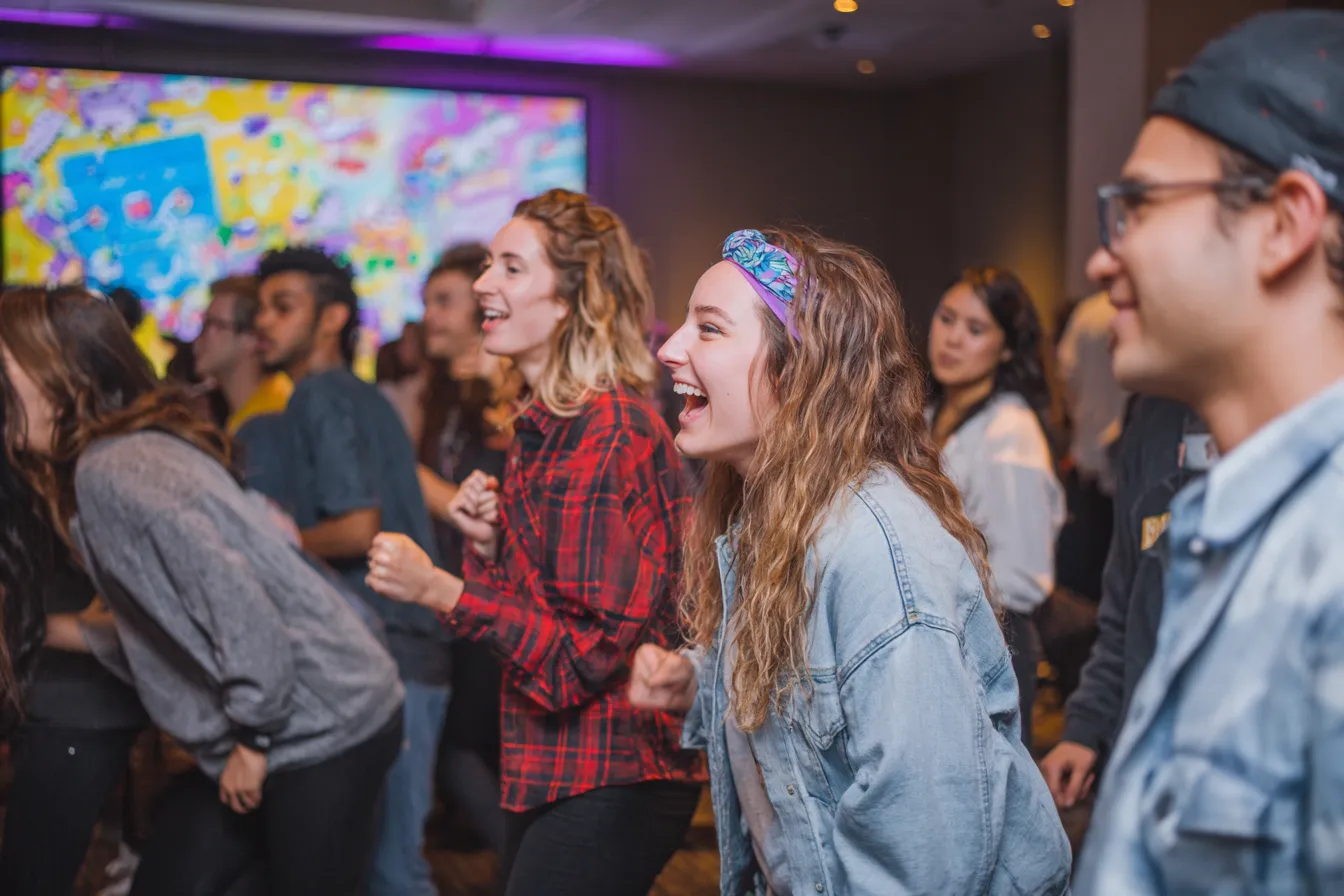 Toeschouwers kijken enthousiast toe bij een Just Dance zijprogramma tijdens een evenement