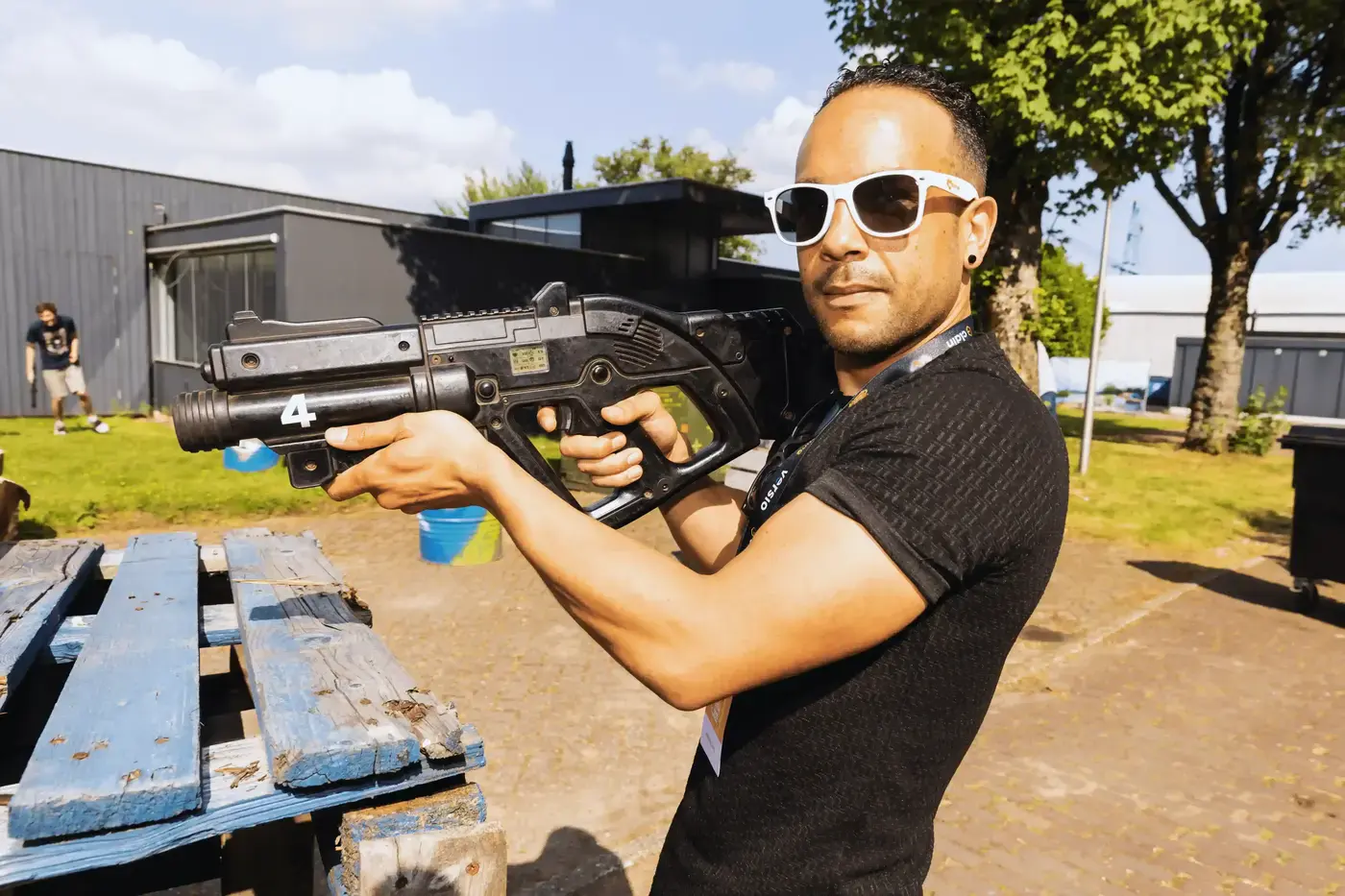 Man met zonnebril richt een professioneel laserwapen tijdens een bedrijfsevenement