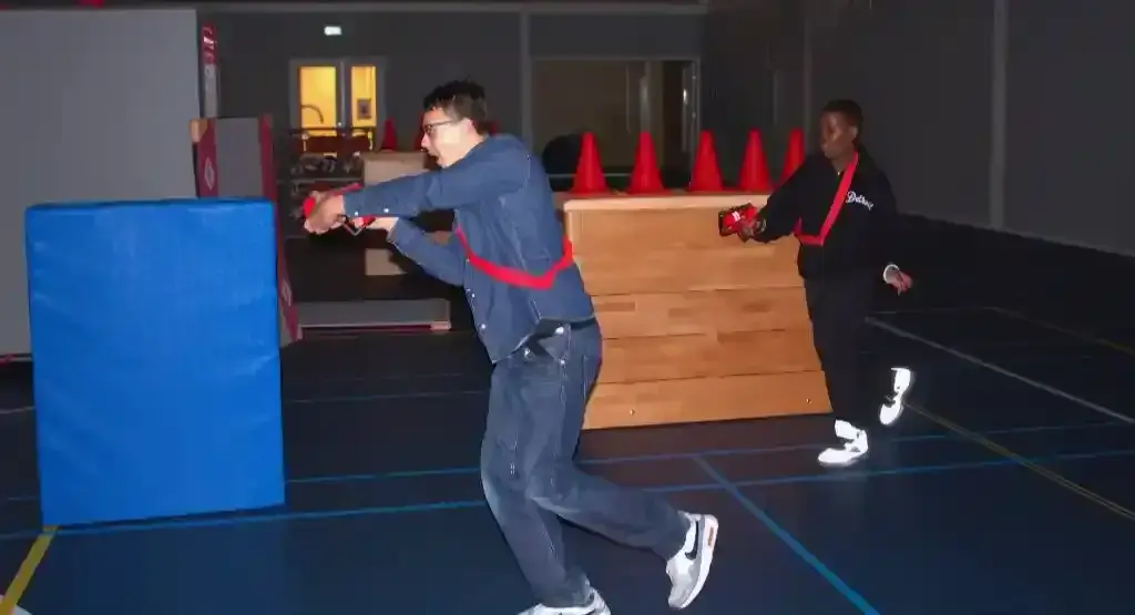 Groep deelnemers speelt lasergamen met professionele laserguns tussen opblaasbare hindernissen