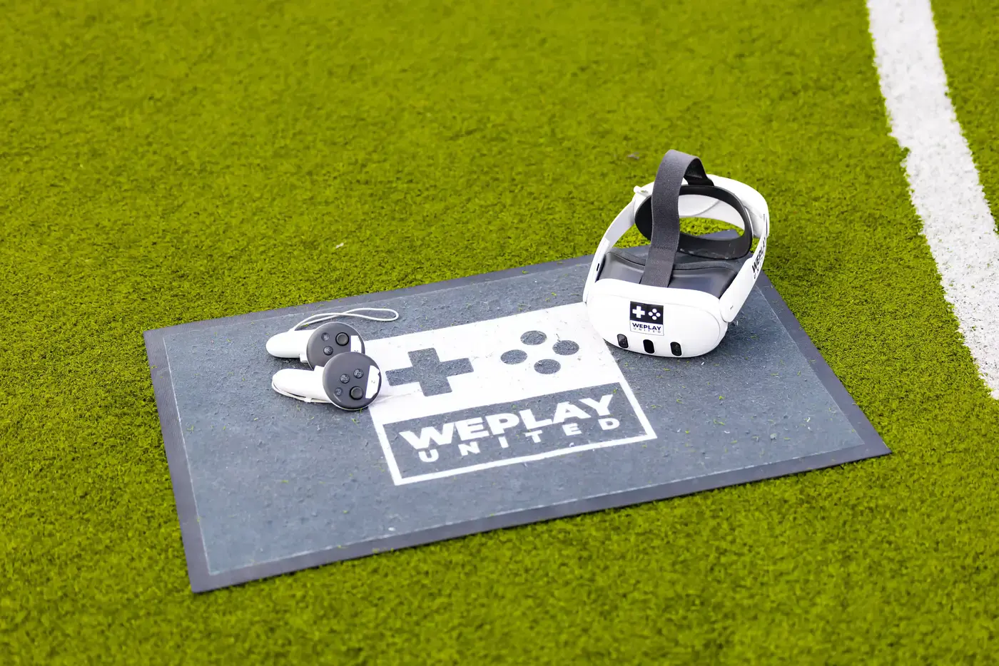 VR-headset met controllers op een WePlay United mat op een kunstgrasveld